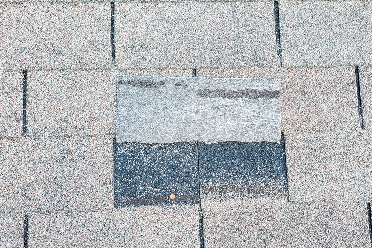 Damaged roof shingles being inspected for an insurance claim